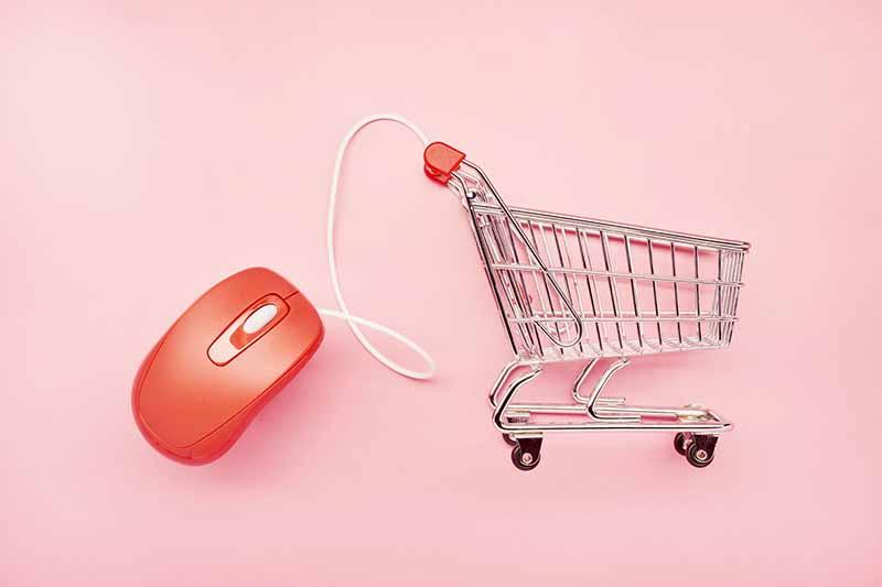 静物小购物车和粉红色背景的红色电脑鼠标，网上购物